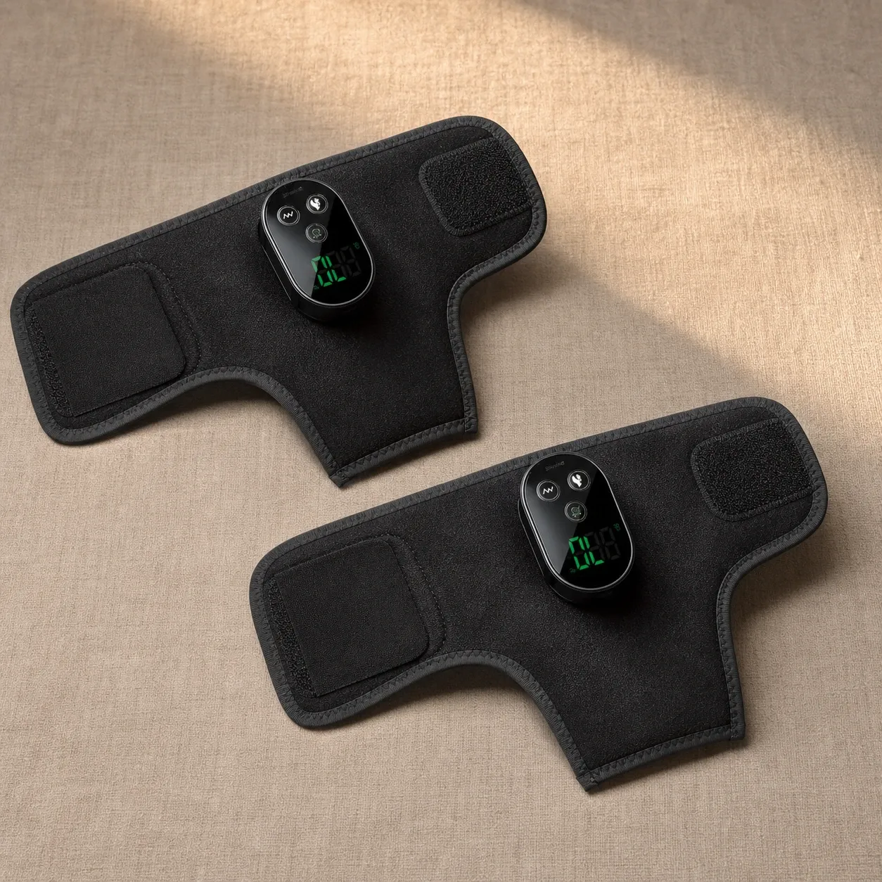 Two cordless heated vibrating ankle wraps laid flat on a textured beige surface, showcasing their sleek design and digital control panel.